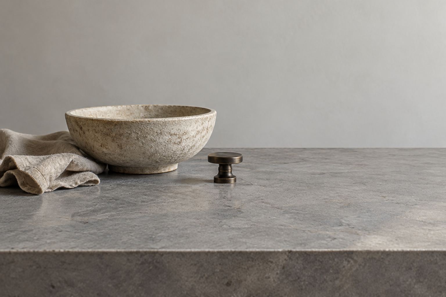 A bowl, folded cloth and a small metal pull on a gray table