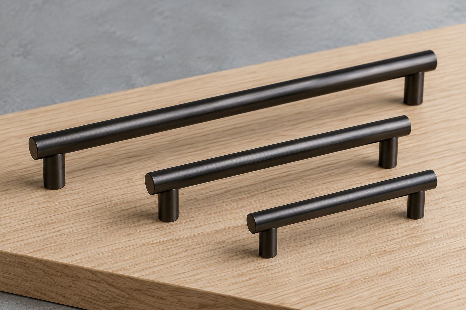 Three dark metal cabinet pulls on pale oak
