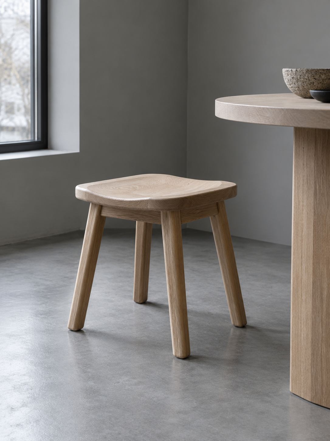 A low wood stool beside a pale side table